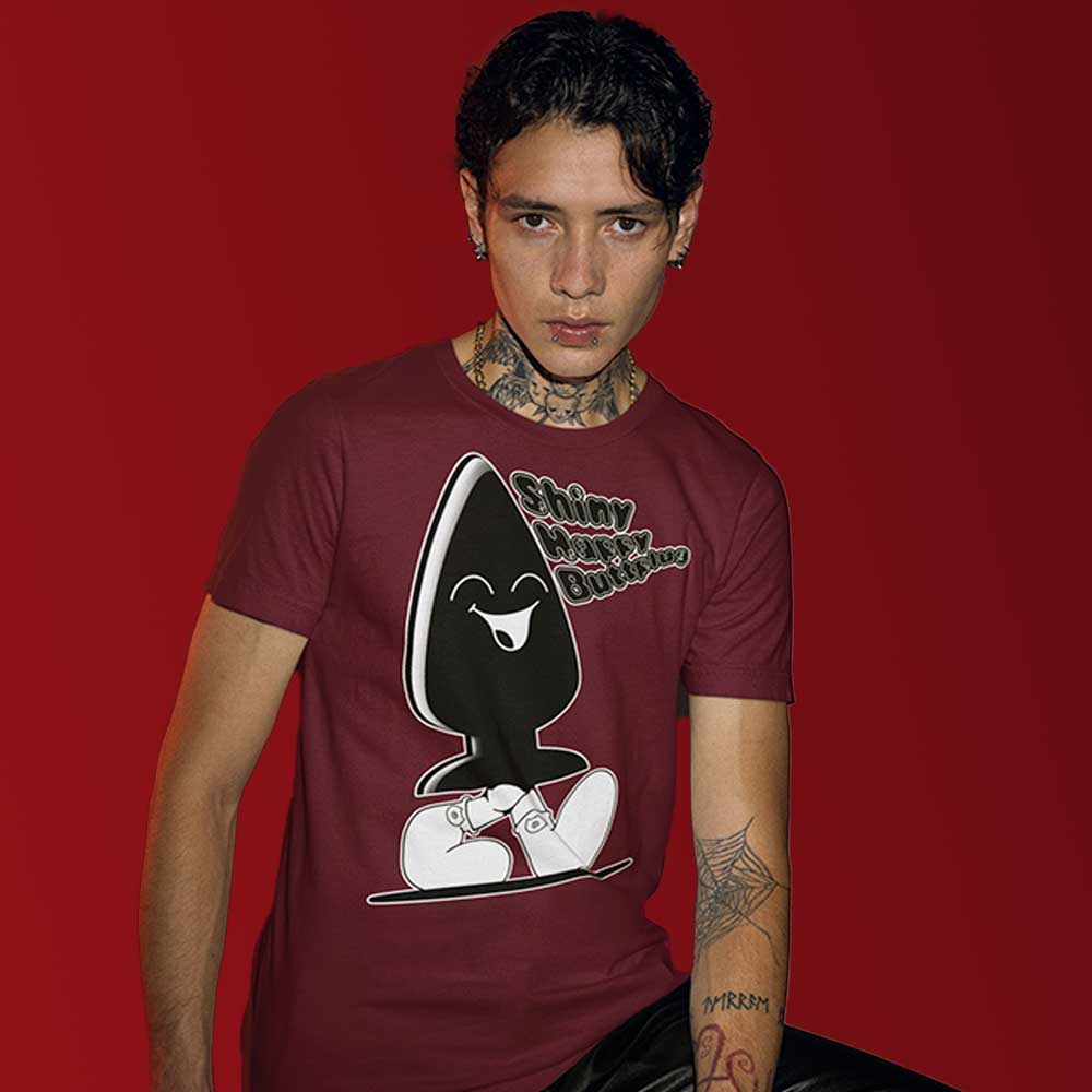 A person wearing a maroon T-shirt with a large graphic print of a character that appears playful and kink-inspired. The character is wearing sunglasses and has a buttplug for a body.