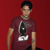 A person wearing a maroon T-shirt with a large graphic print of a character that appears playful and kink-inspired. The character is wearing sunglasses and has a buttplug for a body.
