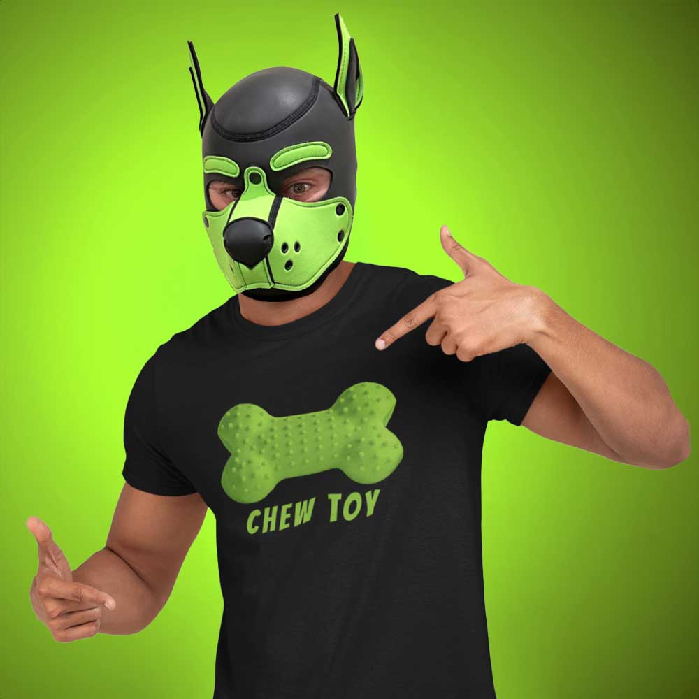 Person wearing a green and black mask pointing to a black t-shirt with a green bone design and 'CHEW TOY' text on a bright green background.