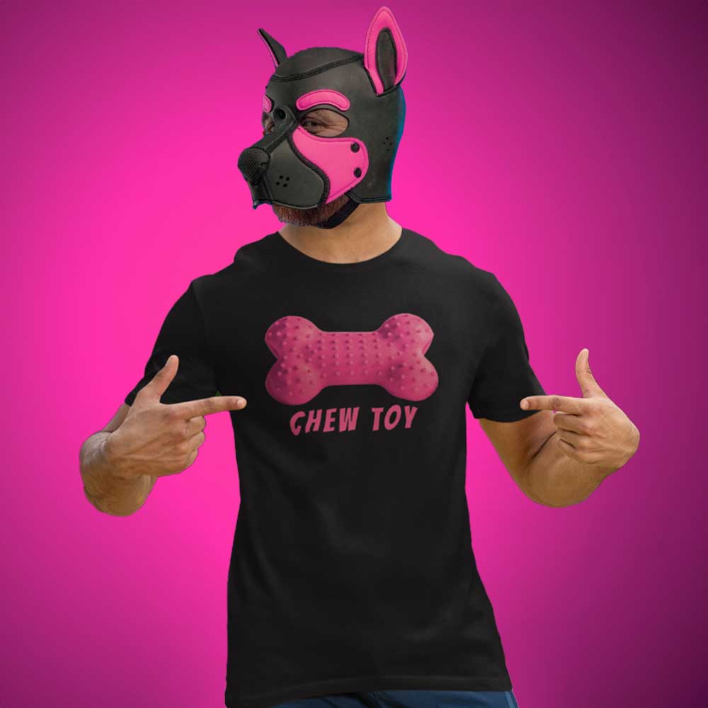 Person wearing a black t-shirt with a pink bone design and 'CHEW TOY' text, pointing at the shirt against a pink background.
