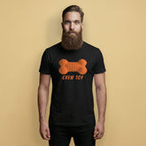 Gay Man wearing a black t-shirt with an orange rubber bone graphic and 'CHEW TOY' text on a beige background - Black and orange Chew Toy pup play t-shirt - gay puppy kink pride tee by BackRoomGear
