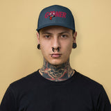 Man wearing a navy cap with 'GOONER' text, rolled eyes and hanging tongue on a beige background - Backroom Gear