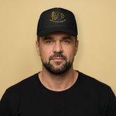 Gay man wearing Happy Little Cigar Pig trucker cap with cartoon pig smoking cigar graphic on black mesh snapback hat - Backroom Gear