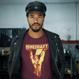 Man wearing a maroon t-shirt with 'Mineshaft' graphic design in a workshop setting - Retro LGBTQ+ pride t-shirts US UK – Gay pride shirts collection – Made-to-order gay apparel