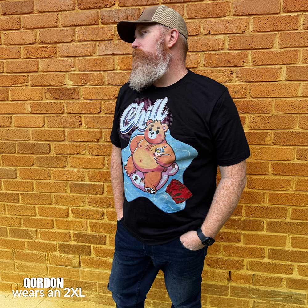 Gay bear wearing a 2xl black t-shirt with a bear graphic and 'Chill' text against a brick wall - Bear Pool Pride T-Shirt | Chubby Bear Graphic Tee – Gay pride shirts collection – LGBTQ+ pride t-shirts US UK – Made-to-order gay apparel