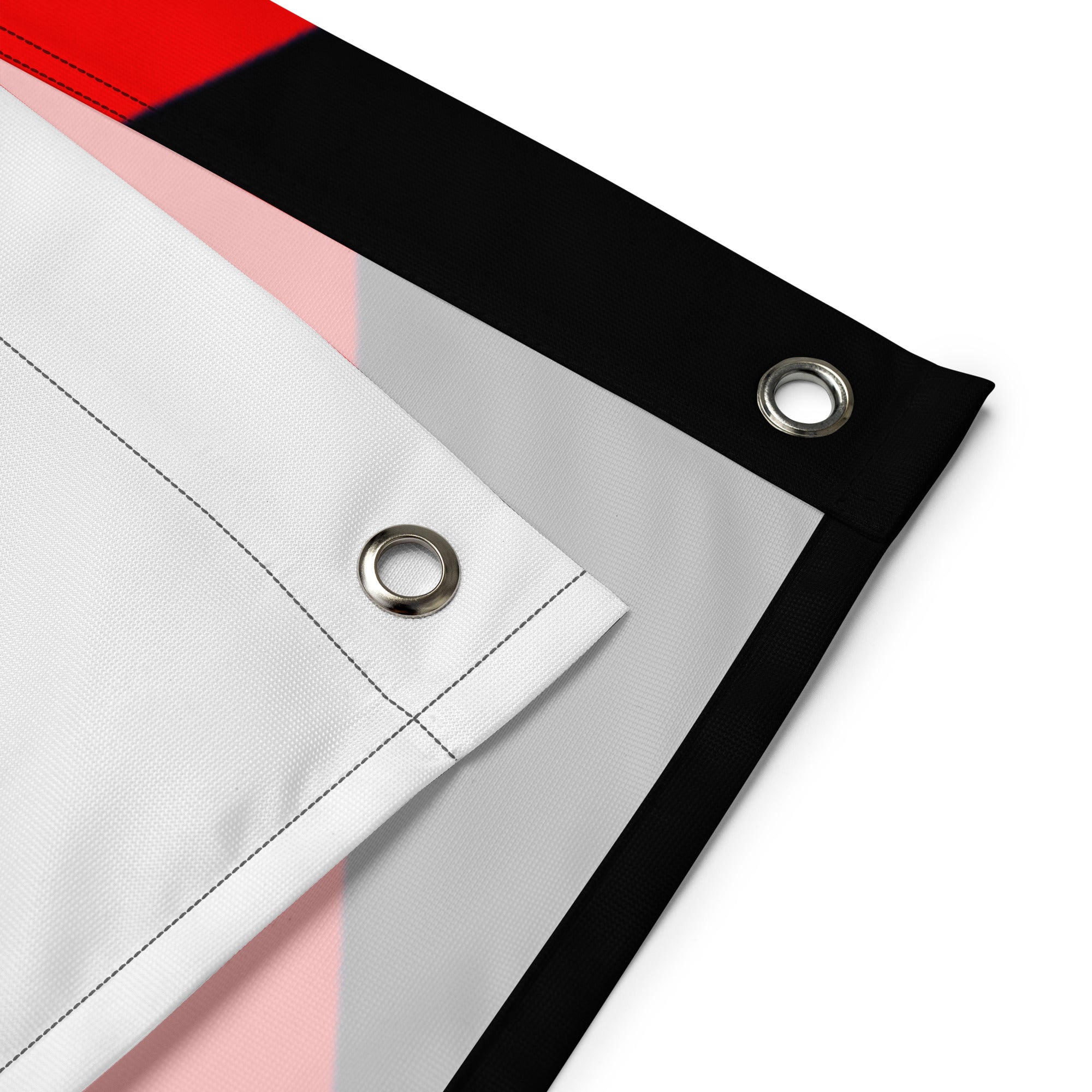 Overlapping corners of the Rubber Pup Pride Flag showing two silver grommets, stitched hems and the pale reverse.
