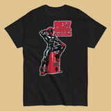 black t-shirt with a man in latex rubber with red helmet and shoes sitting on top of a square barrel of lube graphic design on a beige background - Black and red Sexy Rubber Flanders t-shirt - kinky latex rubber kink tee by BackRoomGear