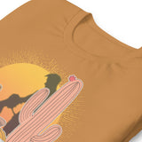 folded toast brown shirt featuring a sunset with two silhouetted figures, one sitting sucking the one standing, surrounded by cacti - Vintage Brokeback Cowboy t-shirt - western gay pride tee by BackRoom Gear