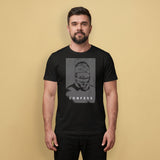 A gay man wearing a black t-shirt with a Blind Jock graphic design and 'CONFESS' text