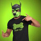 Gay pup wearing a green and black mask pointing to a black t-shirt with a green bone design and 'CHEW TOY' text on a bright green background.