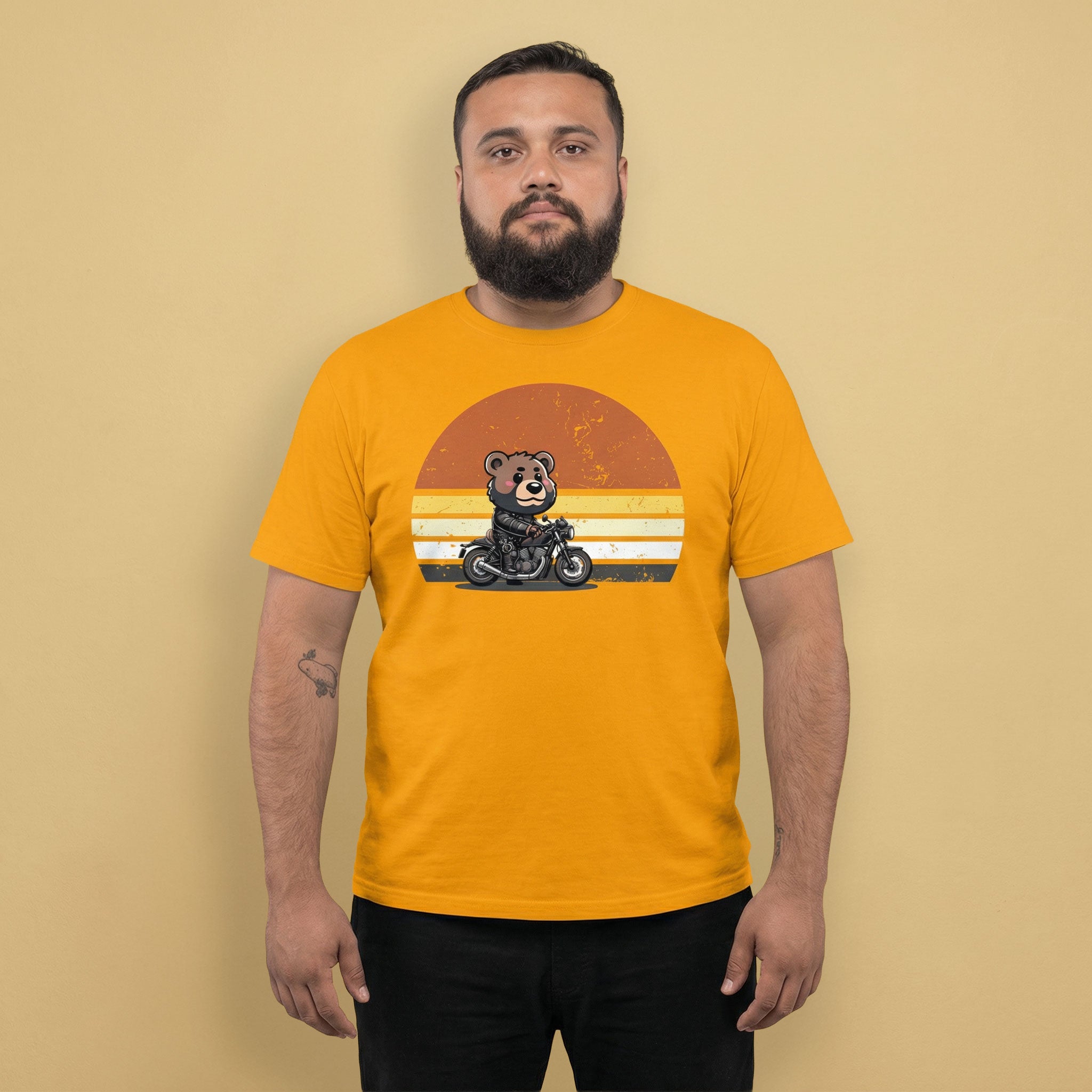 Gay bear wearing a yellow gold t-shirt with a bear on a motorcycle graphic against a beige background - Leather Biker Bear T-Shirt - Cute Retro Sunset Design – Gay pride shirts collection – LGBTQ+ pride t-shirts US UK – Made-to-order gay apparel