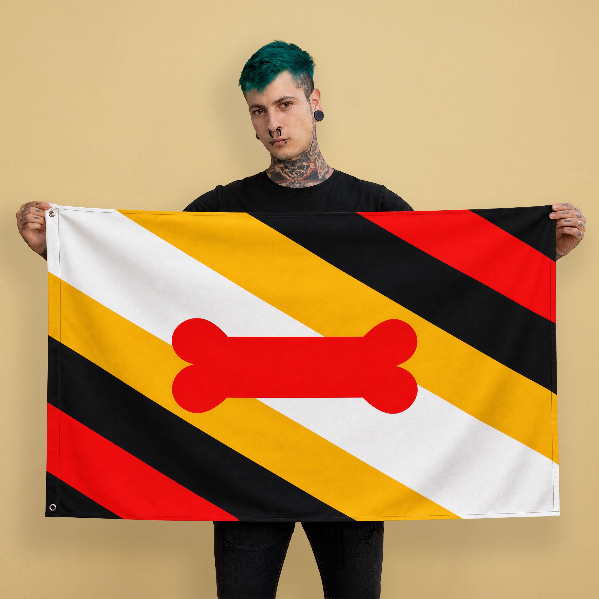 Tattooed male model with teal hair holding the Rubber Pup Pride Flag with diagonal red, black, yellow and white stripes and a red bone.