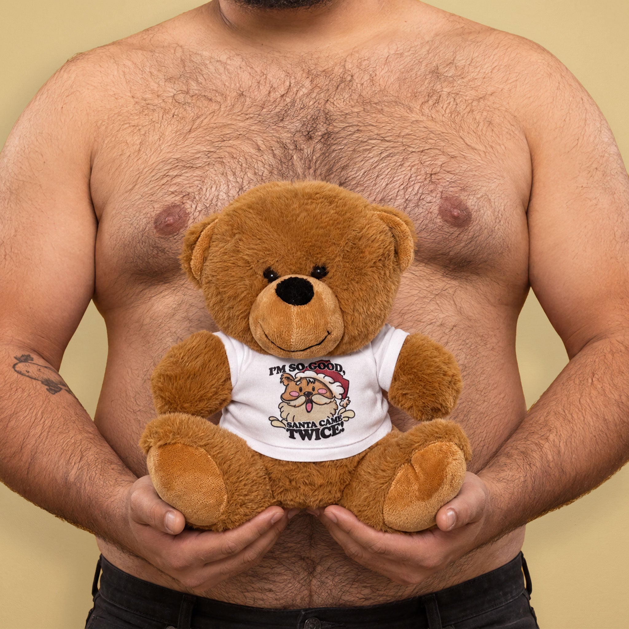 Shirtless guy holding a brown teddy bear wearing a white “I’m So Good, Santa Came Twice” T-shirt.