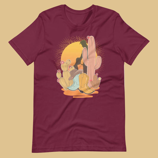 Maroon shirt featuring a sunset with two silhouetted figures, one sitting sucking the one standing, surrounded by cacti - Vintage Brokeback Cowboy t-shirt - western gay pride tee by BackRoom Gear